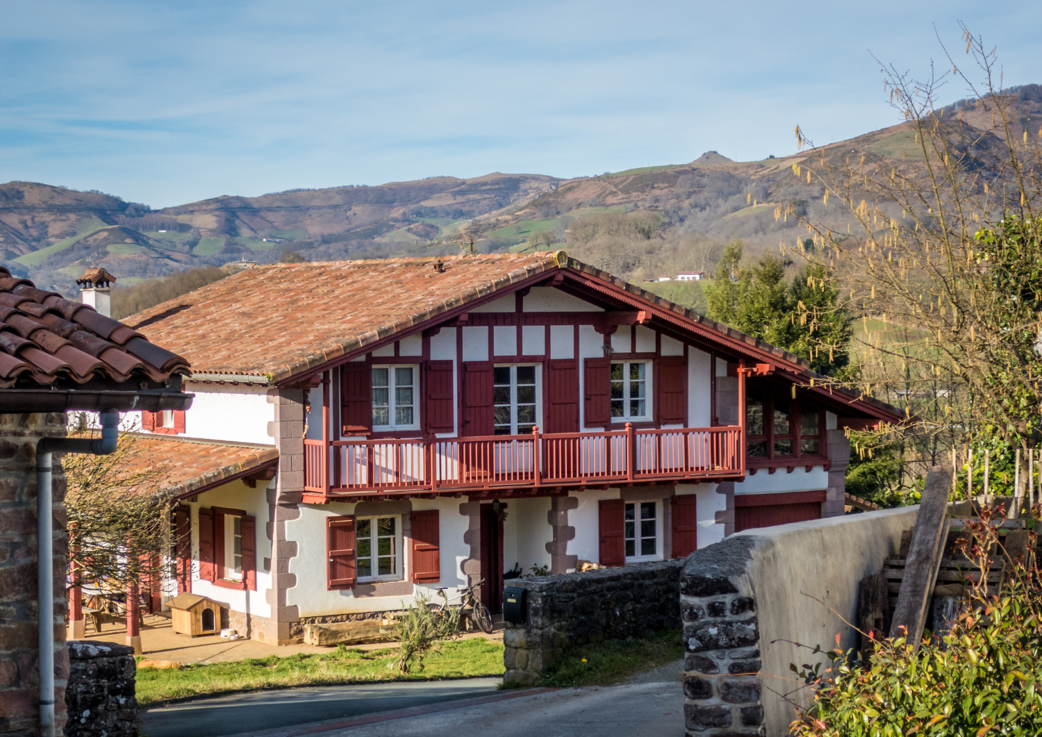 Grande maison entourée de montagnes et d'arbres.